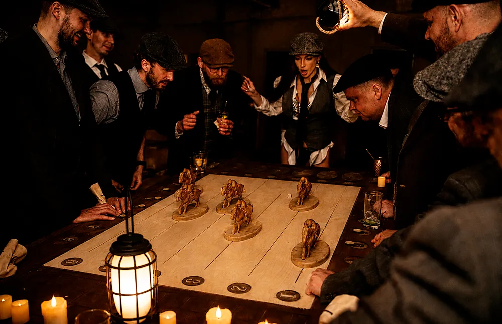 Guests gather around a horse racing table at the Peaky Blinders Black Penny Society event by DorianGrey in Tallinn